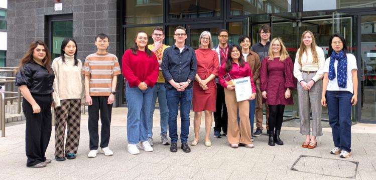 QUB Researchers stand in a group outside the front door of PGJCCR